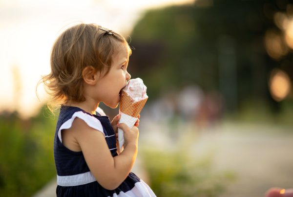 Beautiful baby girl eating ice cream on a sunny summer day.