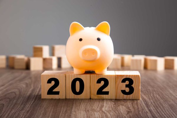 A lighted piggy bank sits atop wood blocks that read "2023."