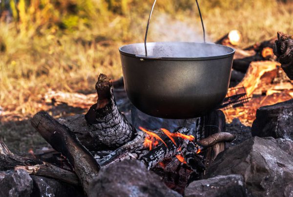 A steaming cast iron pot hangs over an open fire.